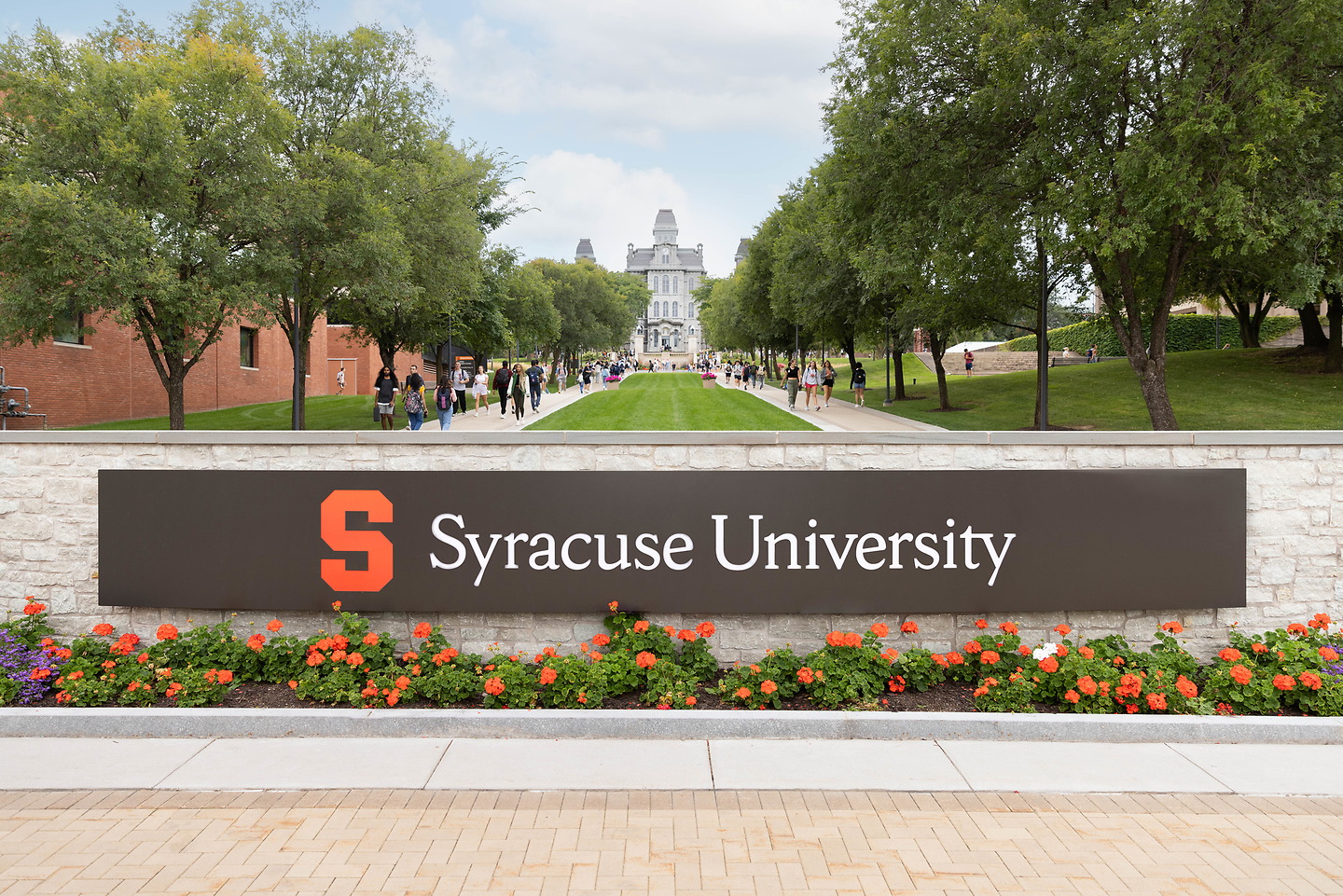 Sign reading 'Syracuse University' with pathway leading to Hall of Languages in the Summer